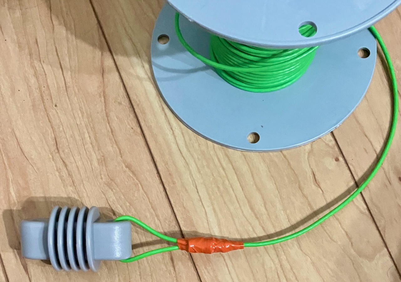end insulator attached to end of wire with loop sleeve covered in electrical tape